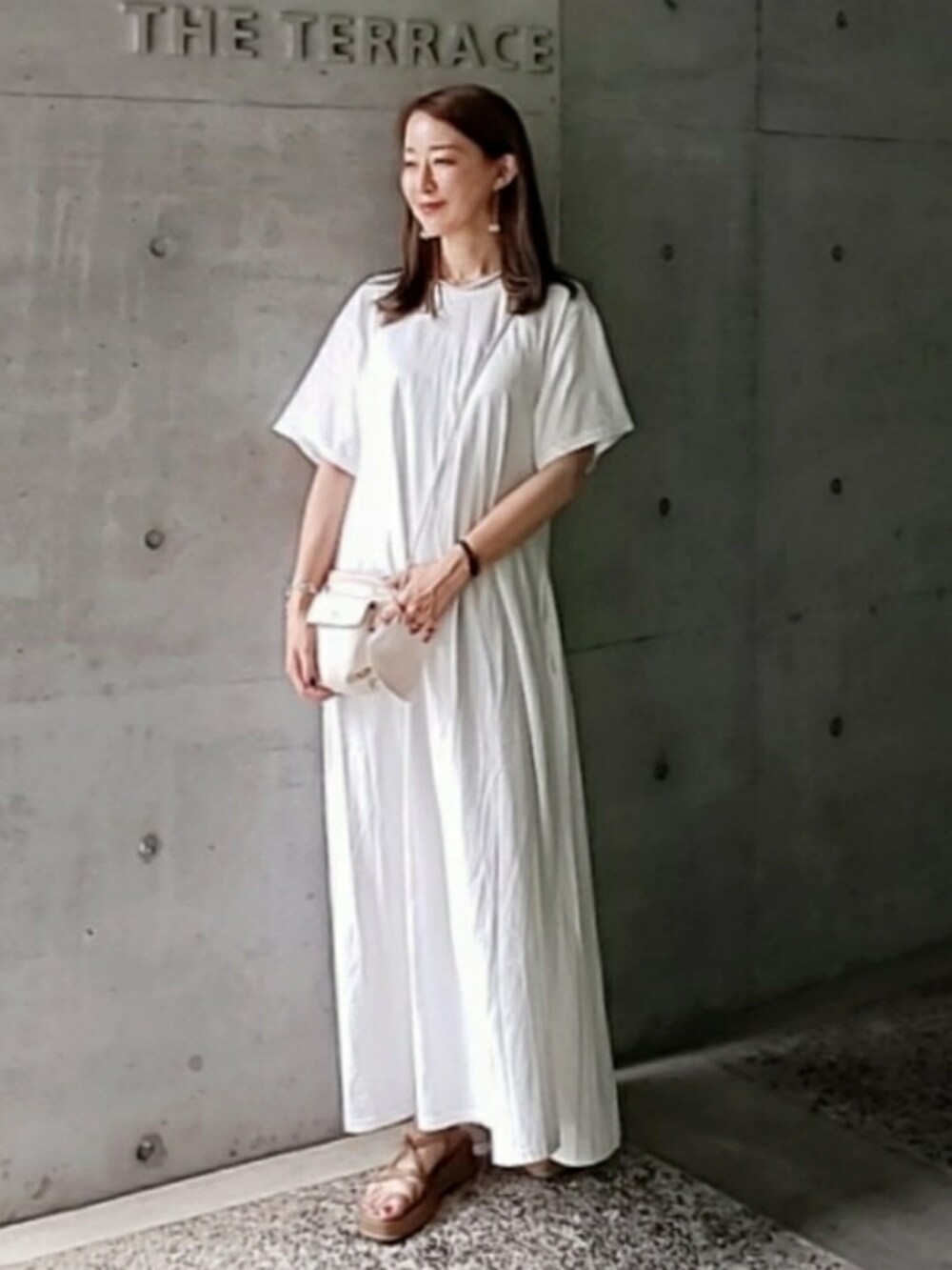 ホワイト系のワンピース、ホワイト系のショルダーバッグ、ブラウン系のサンダルを着用したレディースの夏コーディネートの3枚目の写真