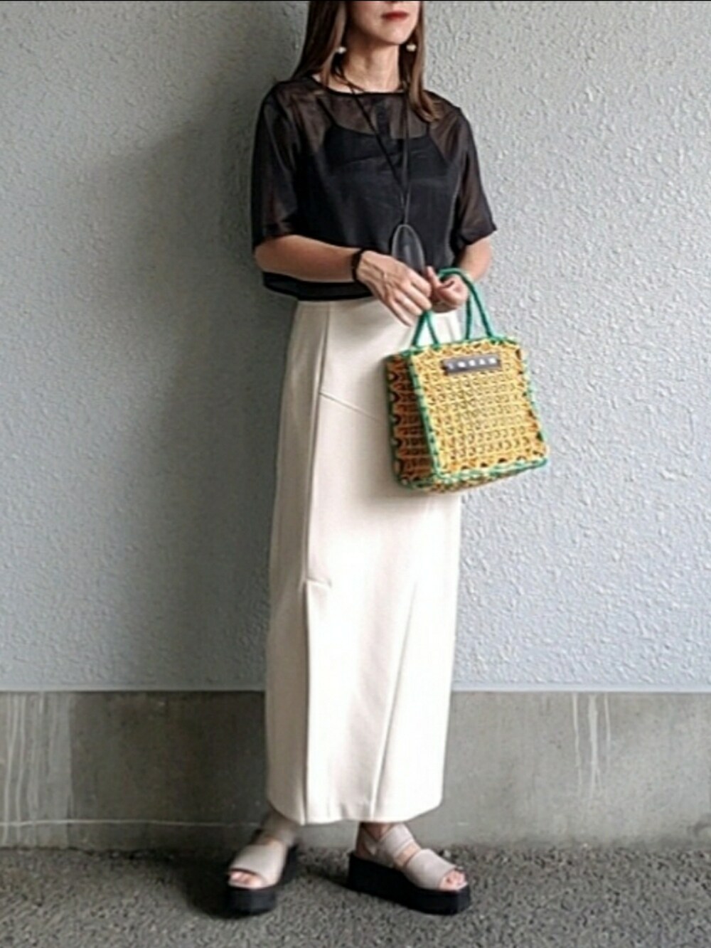 ブラック系のトップス、ベージュ系のスカート、グレー系のサンダルを着用したレディースの夏コーディネートの4枚目の写真