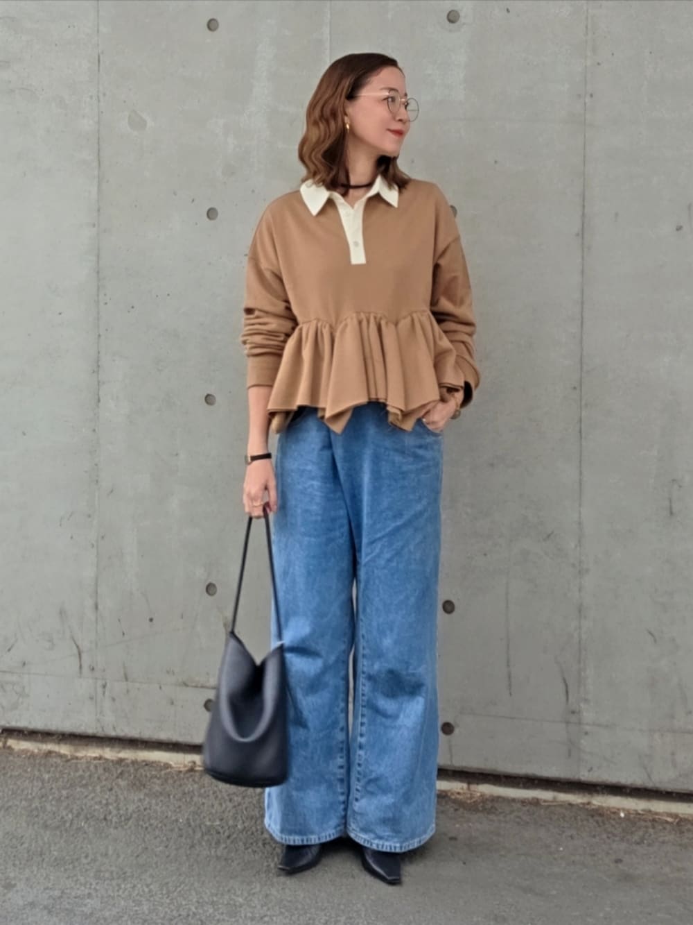 イエロー系のスウェット、ブルー系のデニムパンツ、ブラック系のパンプスを着用したレディースの春コーディネートの2枚目の写真