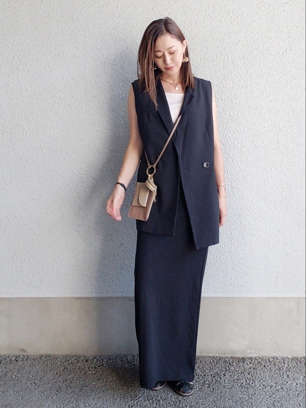 ブルー系のベスト、ブラック系のワンピース、ブラウン系のショルダーバッグを着用したレディースの夏コーディネートの2枚目の写真