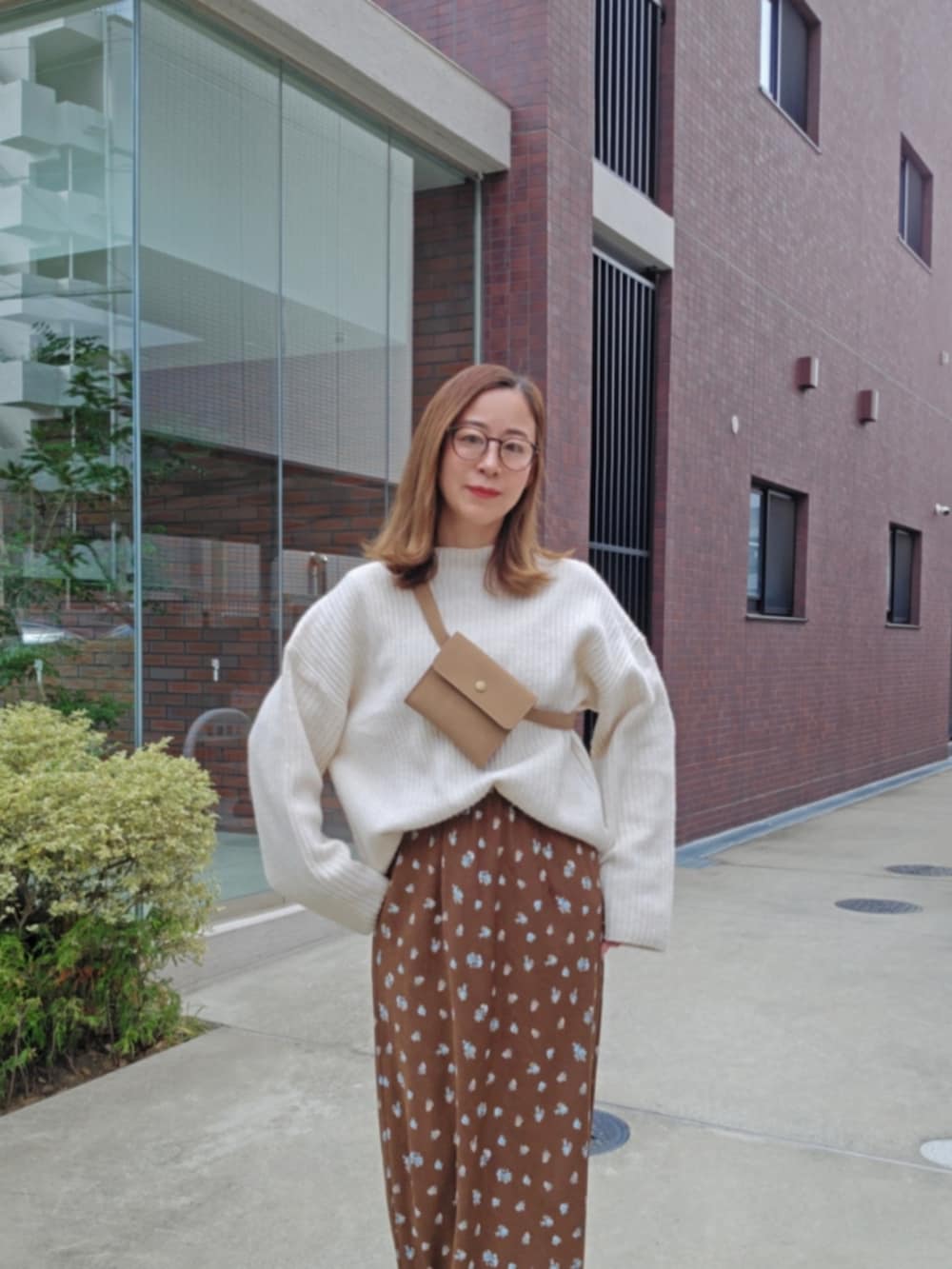 ブラウン系のスカート、ホワイト系のニット/セーター、ブラック系のブーツを着用したレディースの冬コーディネートの3枚目の写真