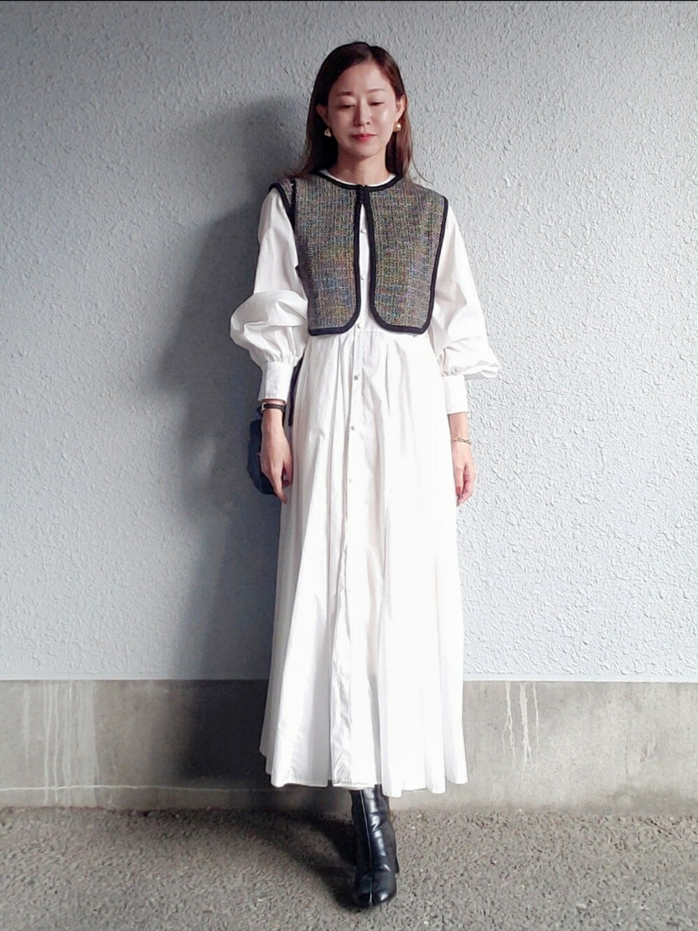 ブラック系のベスト、ブラック系のブーツ、ブラック系のバッグを着用したレディースの秋コーディネートの2枚目の写真