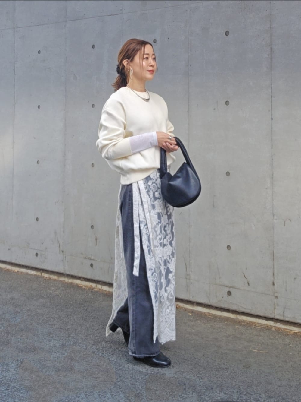 ホワイト系のニット/セーター、ホワイト系のスカート、ブラック系のデニムパンツを着用したレディースの冬コーディネートの2枚目の写真