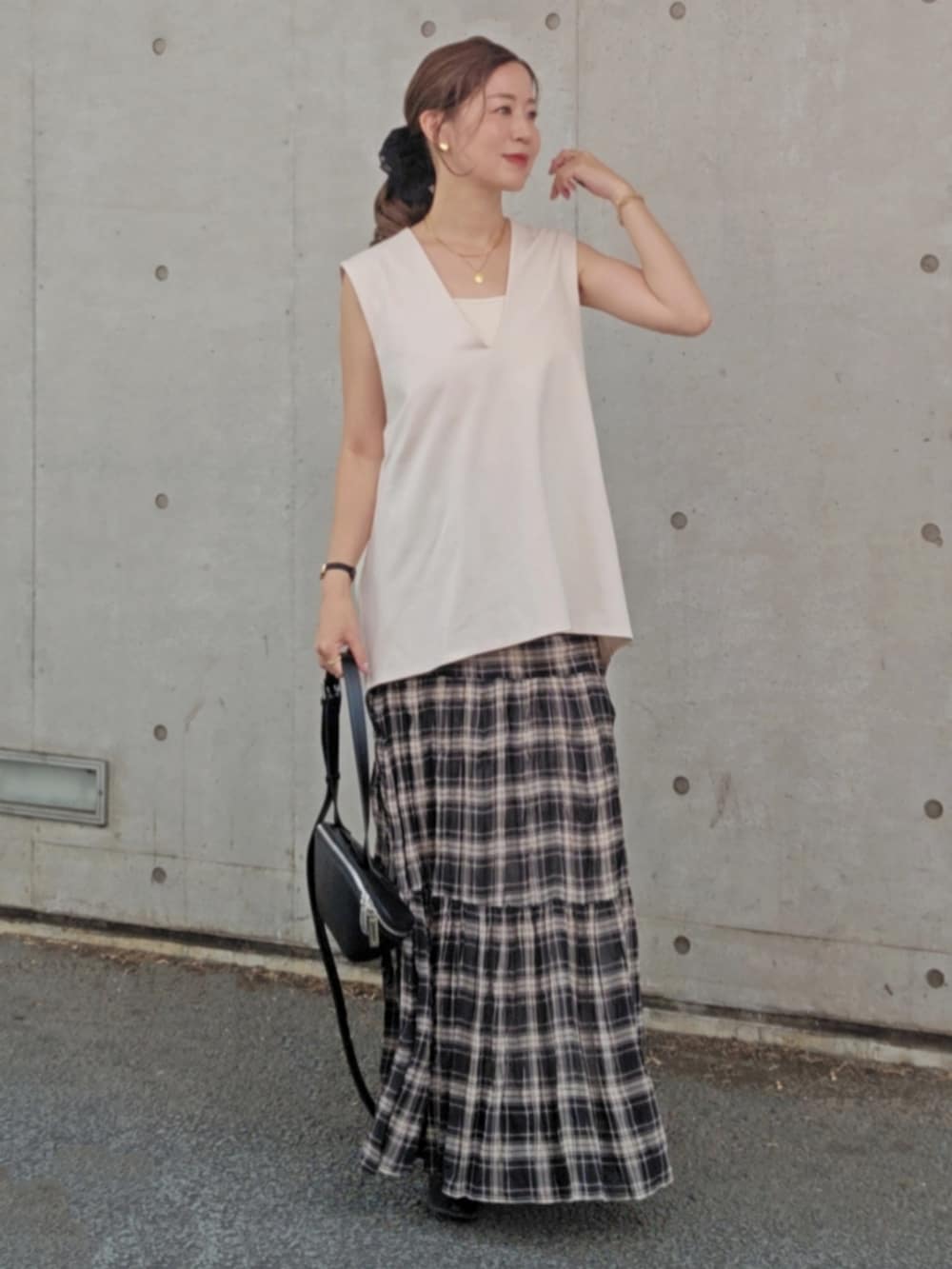ホワイト系のベスト、ブラック系のスカート、ブラック系のショルダーバッグを着用したレディースの夏コーディネートの3枚目の写真