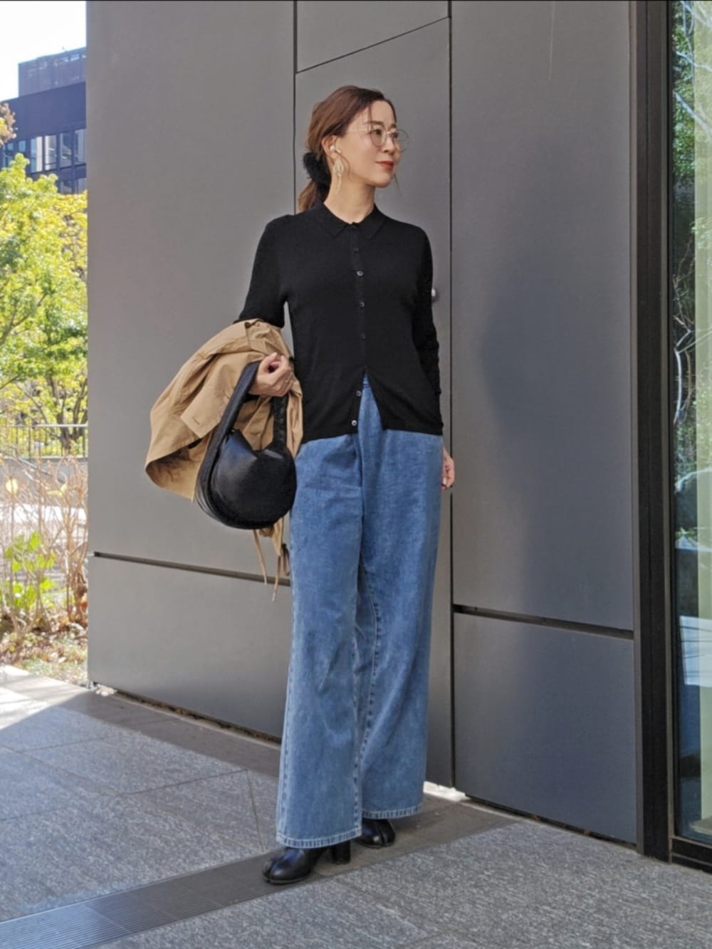 ベージュ系のトレンチコート、ブラック系のトップス、ブルー系のデニムパンツを着用したレディースの冬コーディネートの3枚目の写真