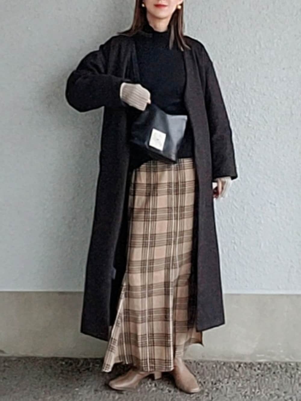 ブラック系のニット/セーター、ブラウン系のスカート、ベージュ系のブーツを着用したレディースの冬コーディネートの2枚目の写真