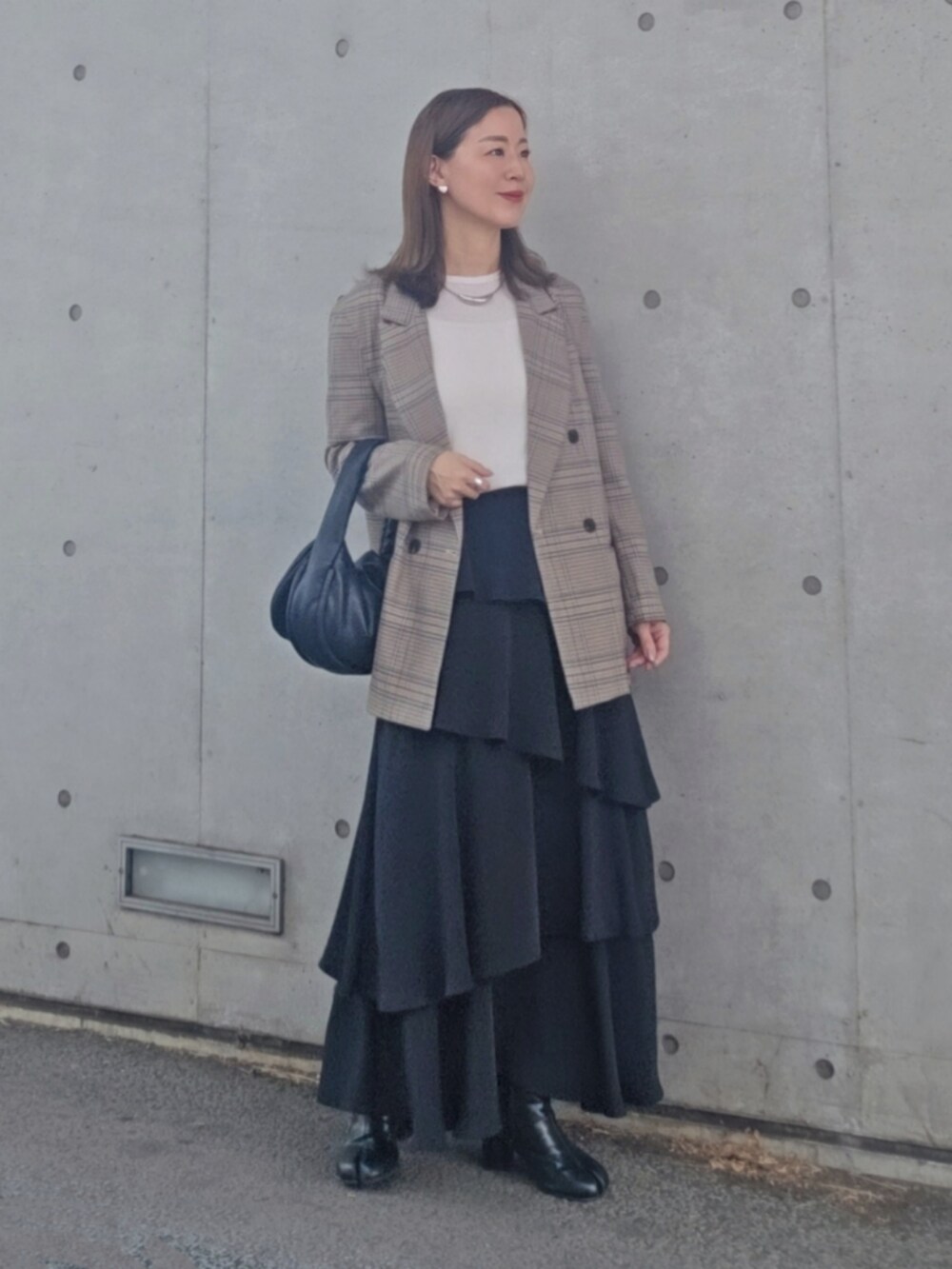 ブラック系のスカート、ブルー系のテーラードジャケット、ブラック系のブーツを着用したレディースの春コーディネートの2枚目の写真