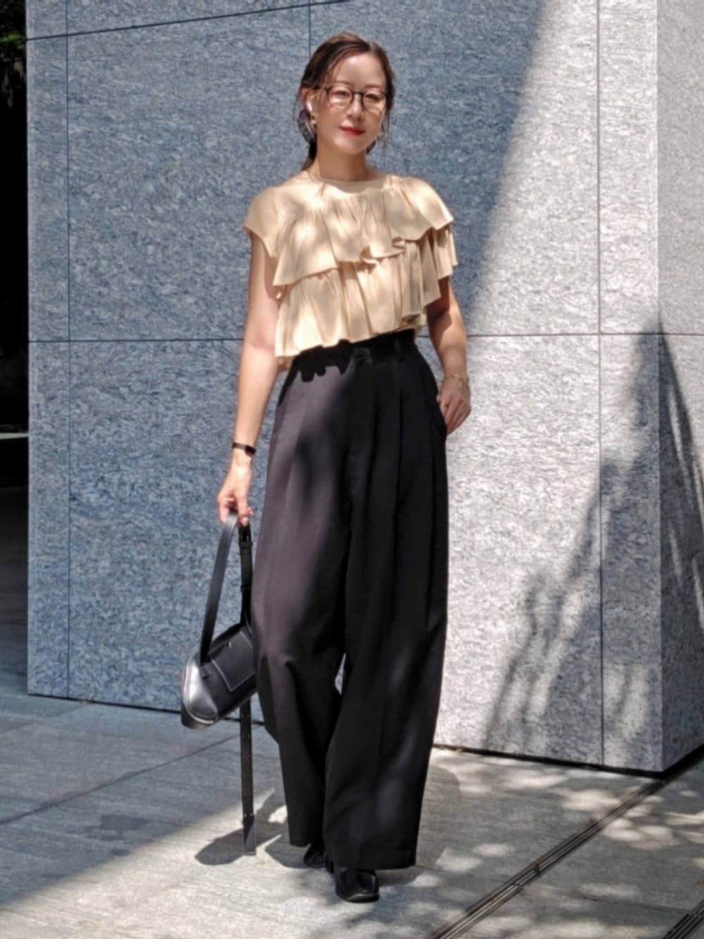 ベージュ系のシャツ/ブラウス、ブラック系のスラックス、ブラック系のブーツを着用したレディースの夏コーディネートの2枚目の写真