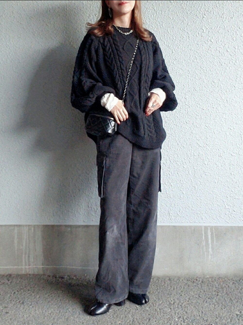 グレー系のパンツ、ブラック系のブーツ、ブラック系のニット/セーターを着用したレディースの秋コーディネートの5枚目の写真