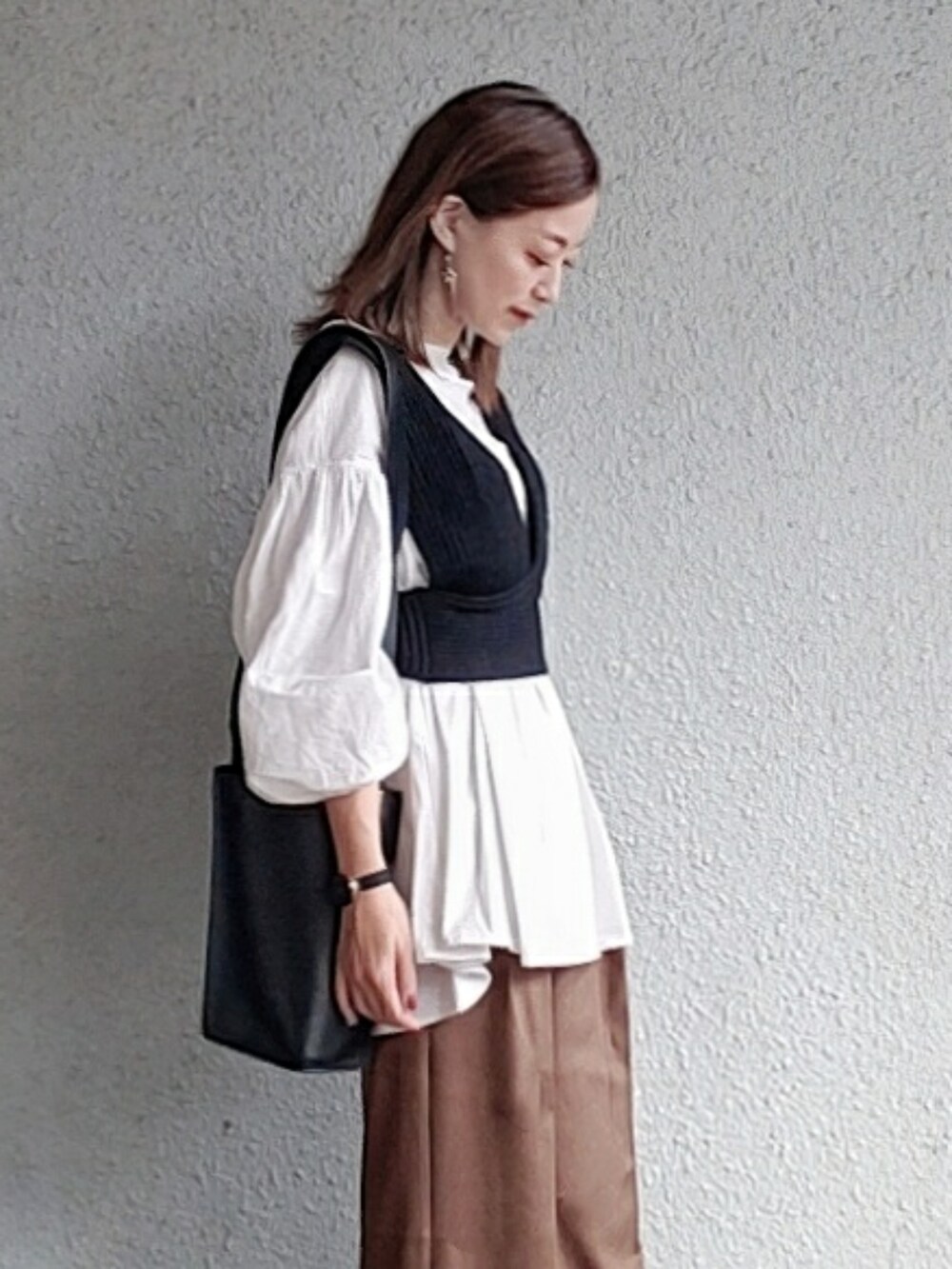 ブラウン系のパンツ、ブラック系のベスト、ホワイト系のシャツ/ブラウスを着用したレディースの冬コーディネートの2枚目の写真