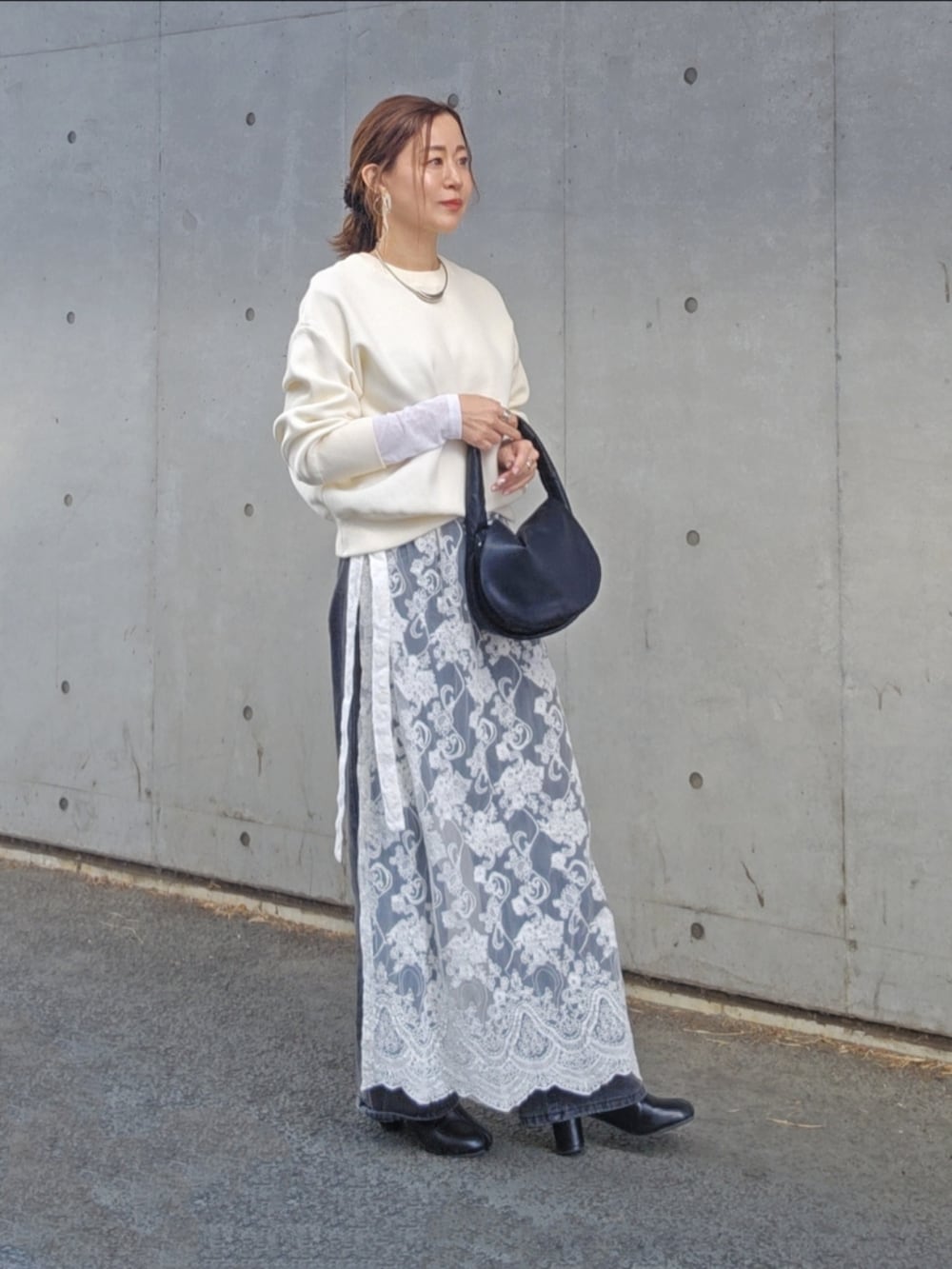 ホワイト系のニット/セーター、ホワイト系のスカート、ブラック系のデニムパンツを着用したレディースの冬コーディネートの3枚目の写真