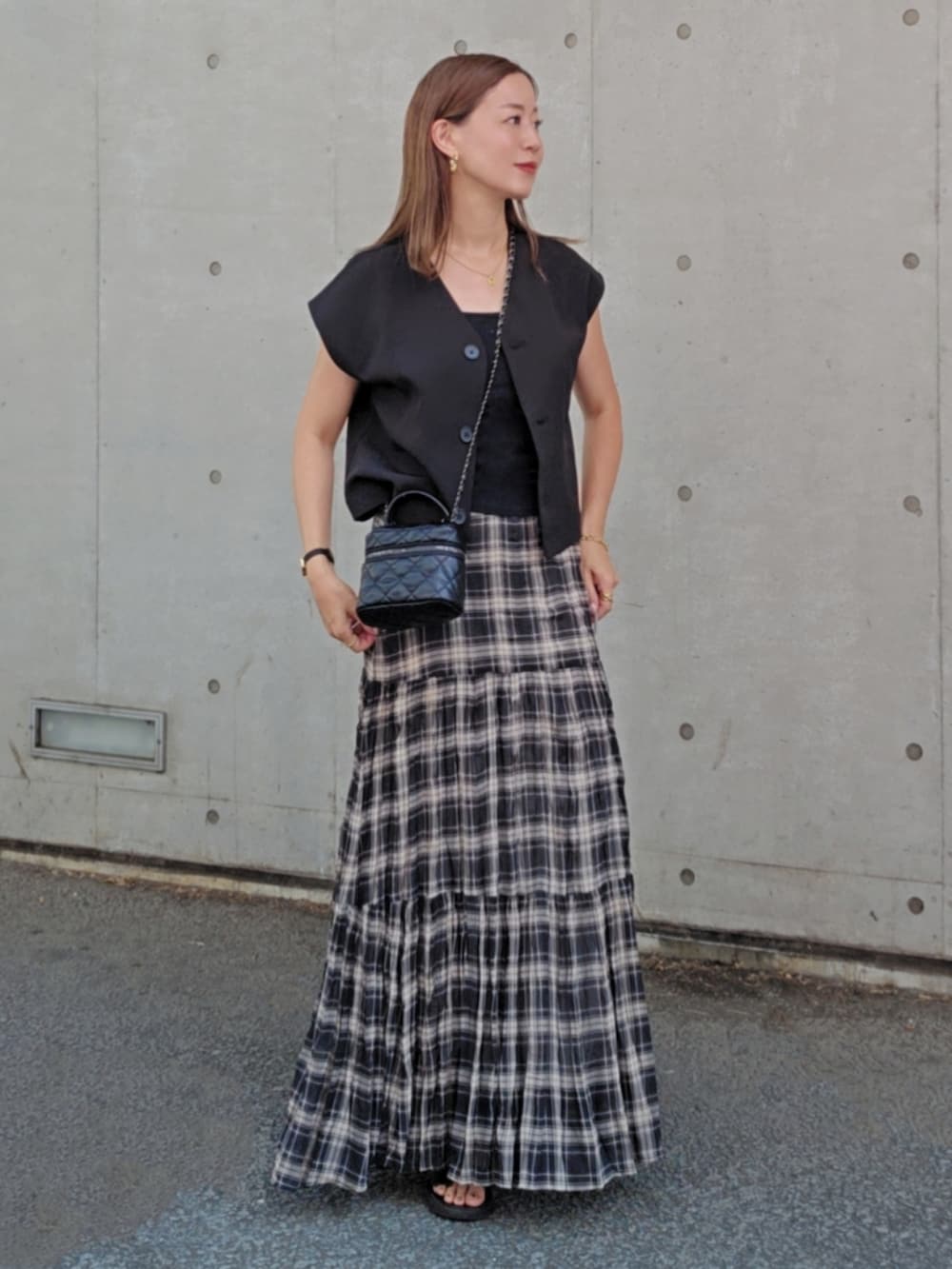 ブラック系のベスト、ブラック系のスカート、ブラック系のバッグを着用したレディースの夏コーディネートの3枚目の写真