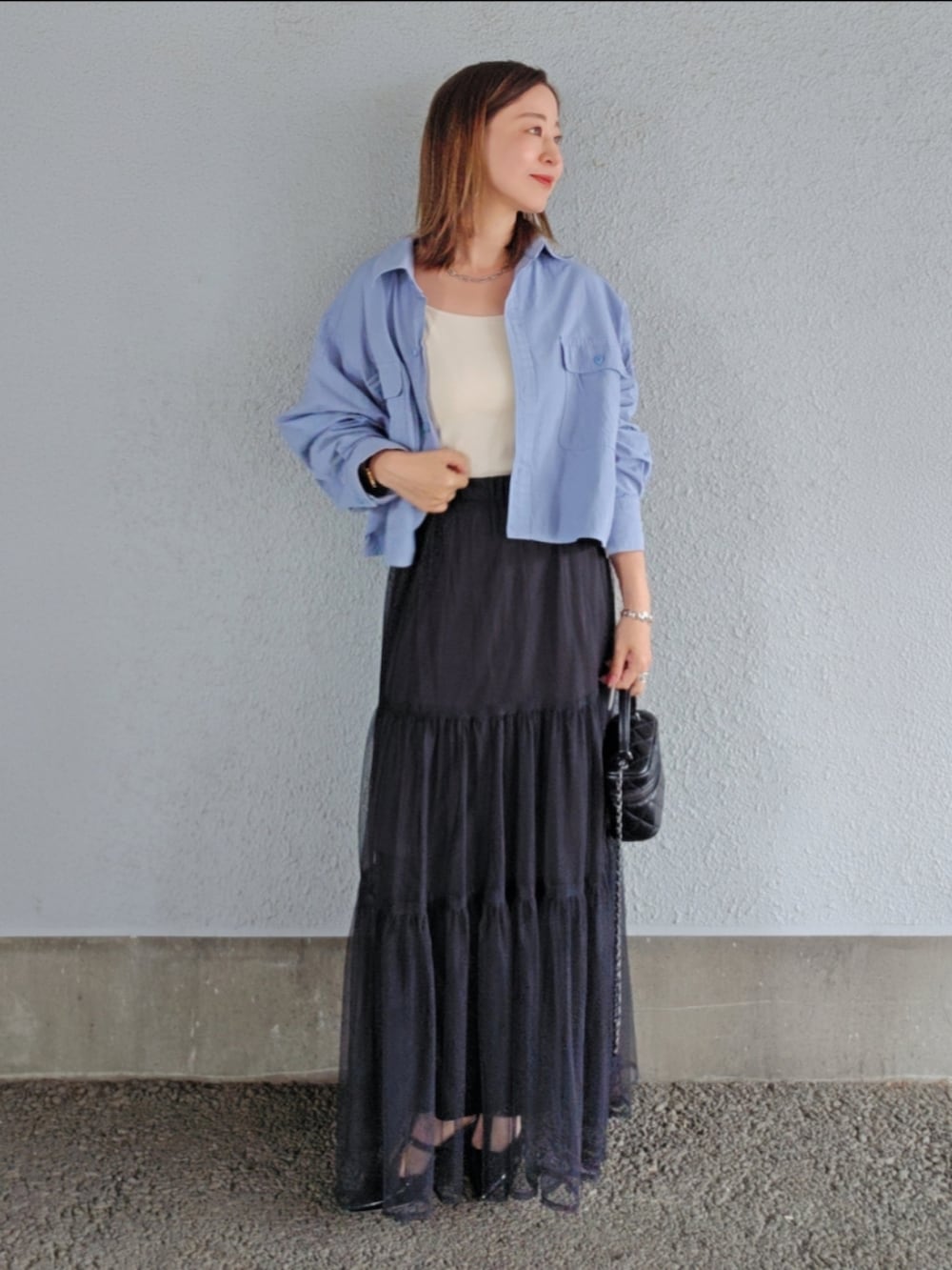 ホワイト系のキャミソール、ブルー系のシャツ/ブラウス、ブラック系のスカートを着用したレディースの春コーディネートの2枚目の写真