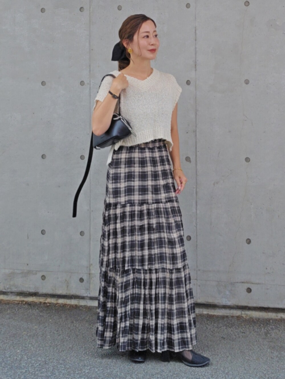 ホワイト系のトップス、ブラック系のスカート、ブラック系のショルダーバッグを着用したレディースの夏コーディネートの3枚目の写真