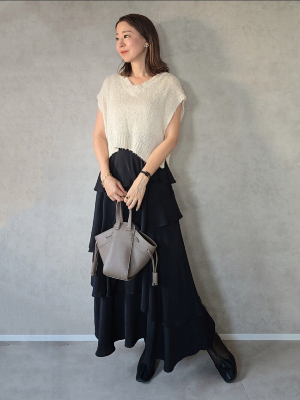 ブラック系のスカート、ブラック系のブーツ、ブラウン系のショルダーバッグを着用したレディースの秋コーディネートの3枚目の写真