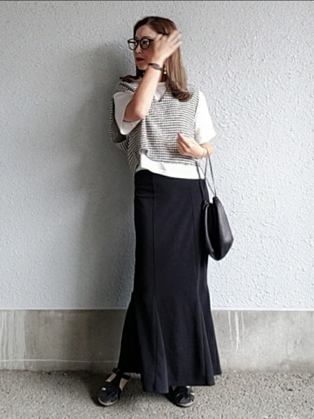 ブラック系のベスト、ブラック系のスカート、ブラック系のサンダルを着用したレディースの春コーディネートの3枚目の写真