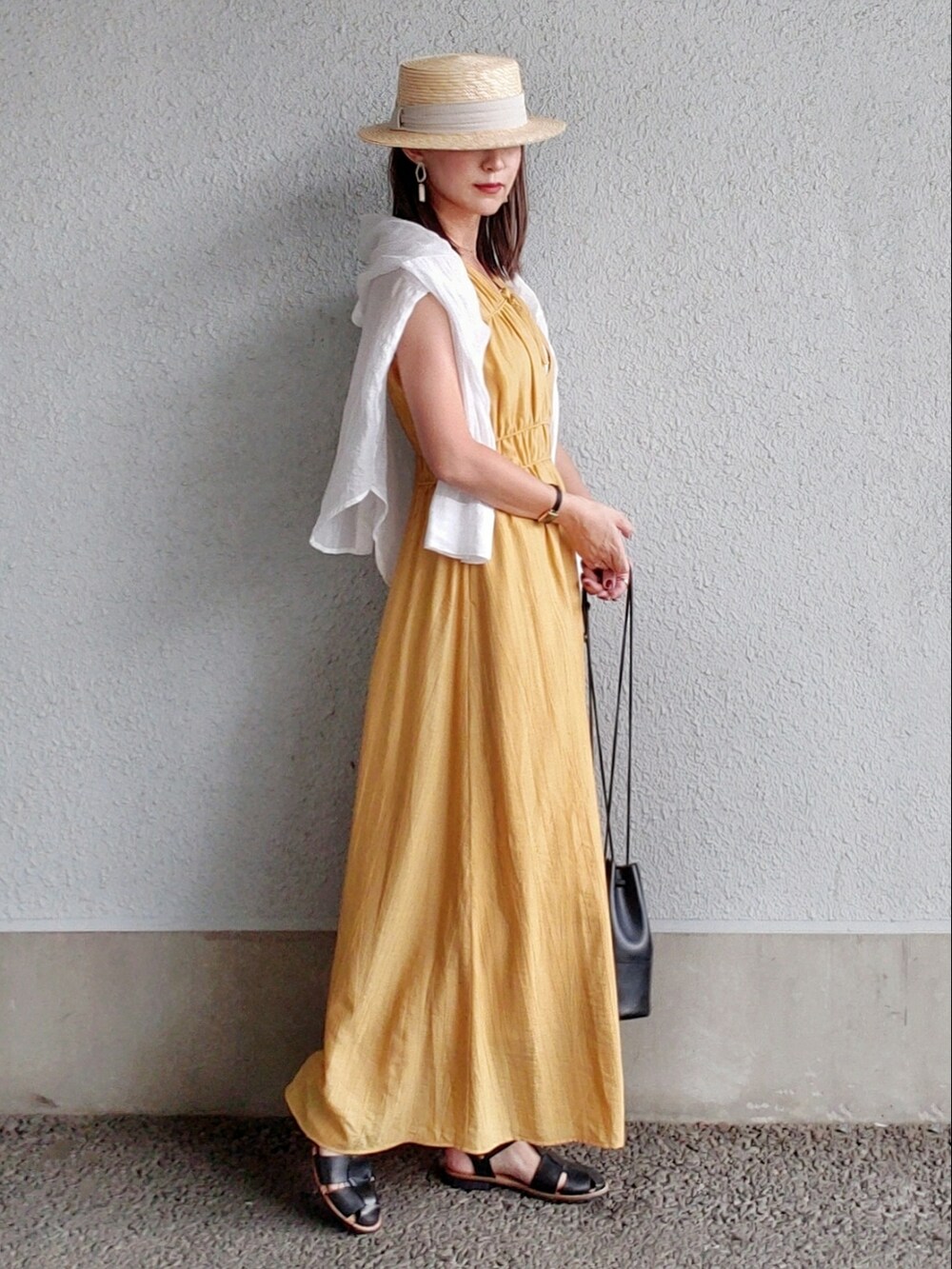イエロー系のワンピース、ホワイト系のタンクトップ、ブラック系のサンダルを着用したレディースの夏コーディネートの2枚目の写真