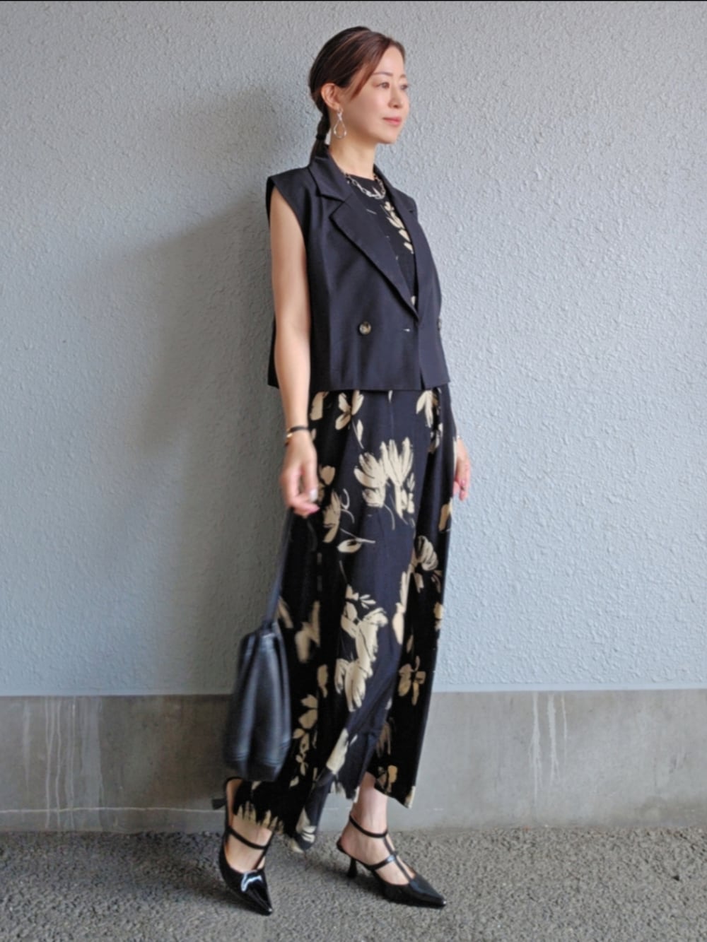 ブラック系のベスト、ブラック系のワンピース、シルバー系のピアス（両耳用）を着用したレディースの春コーディネートの2枚目の写真