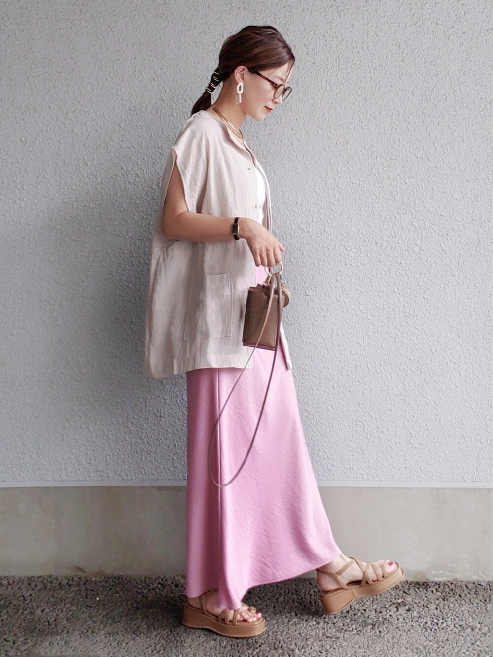 ピンク系のスカート、グレー系のベスト、ブラウン系のサンダルを着用したレディースの夏コーディネートの3枚目の写真