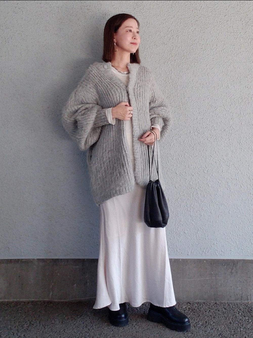 グレー系のカーディガン/ボレロ、ブラック系のバッグ、ベージュ系のスカートを着用したレディースの冬コーディネートの2枚目の写真