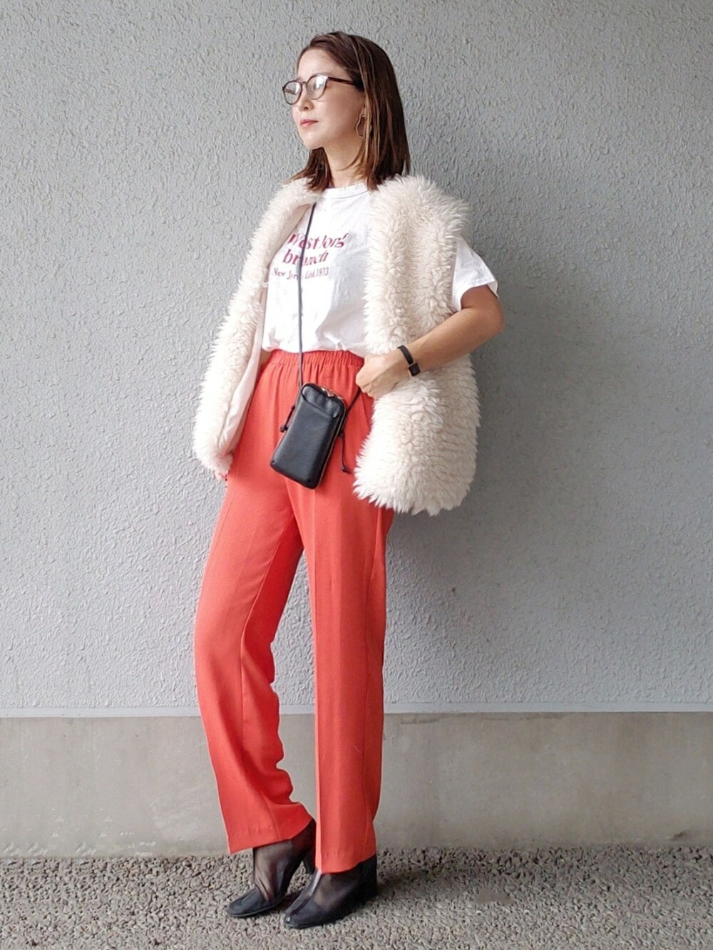 オレンジ系のその他パンツ、ブラック系のブーツ、ホワイト系のベストを着用したレディースの秋コーディネートの2枚目の写真