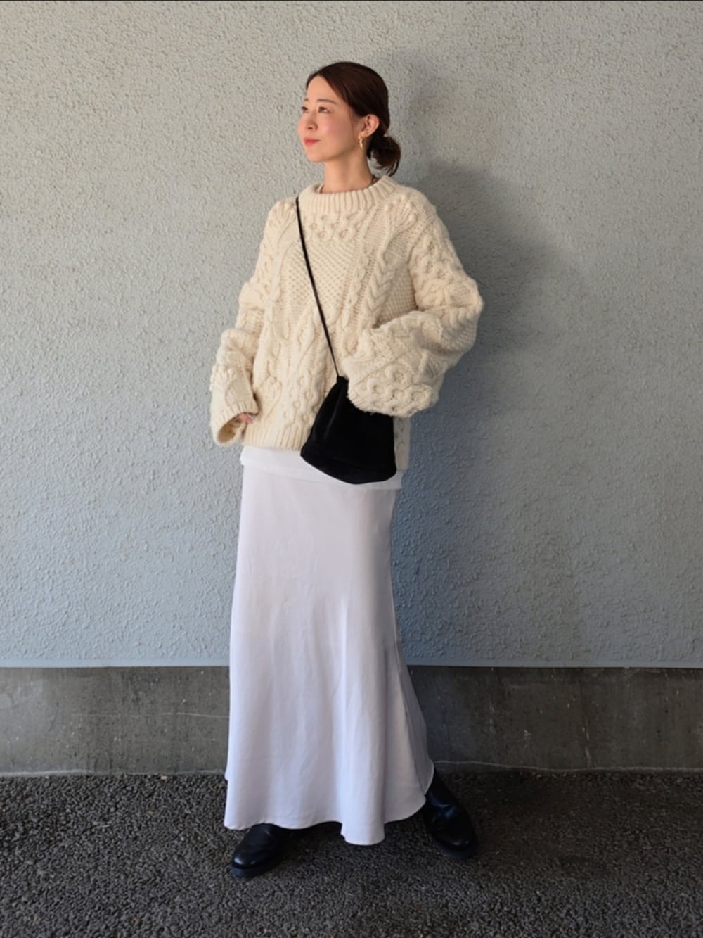 ブラック系のバッグ、ホワイト系のスカート、ホワイト系のニット/セーターを着用したレディースの冬コーディネートの2枚目の写真