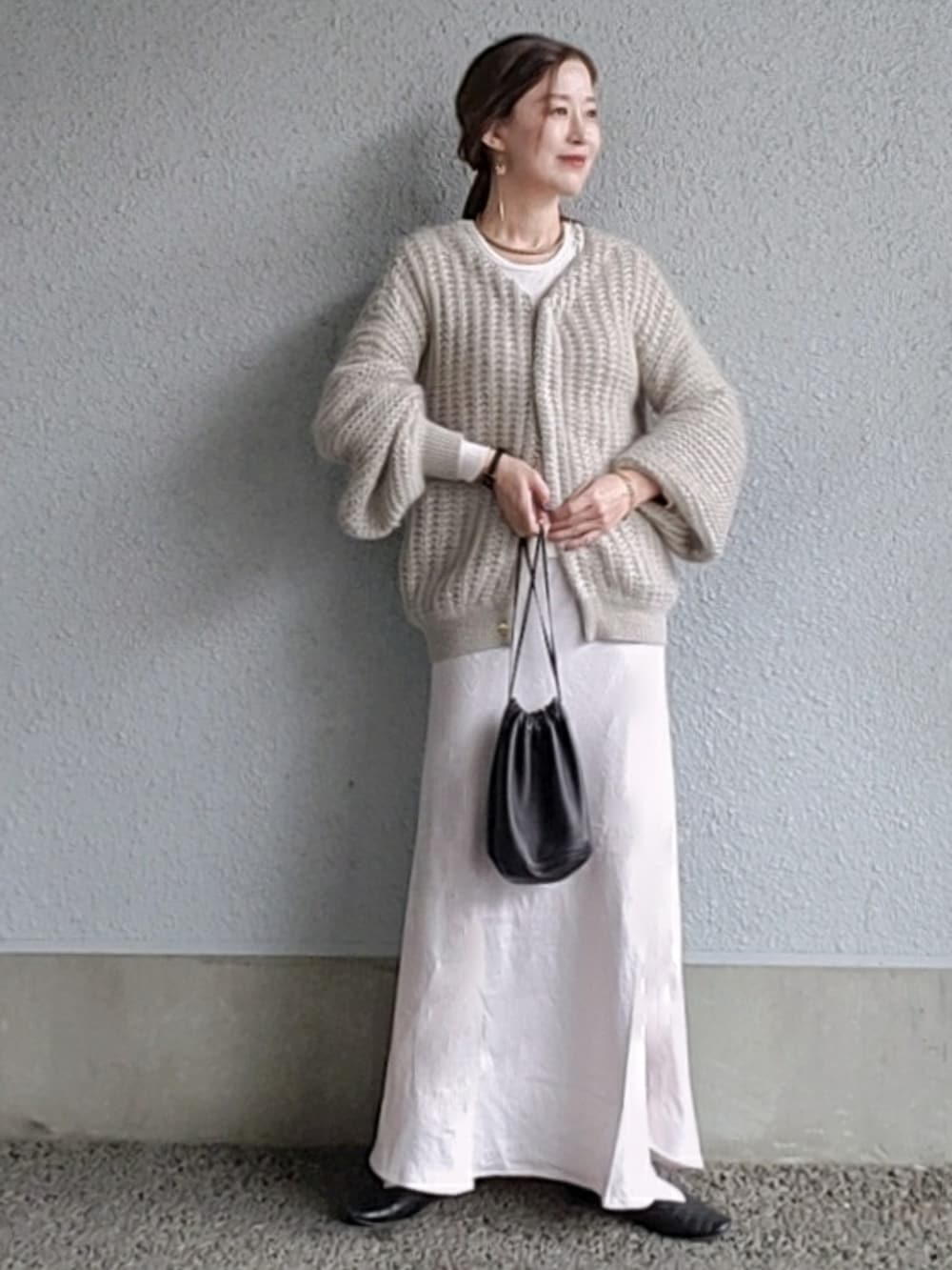 グレー系のカーディガン/ボレロ、ブラック系のバッグ、ホワイト系のスカートを着用したレディースの春コーディネートの3枚目の写真