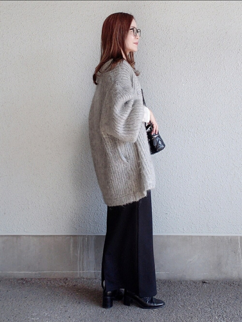 グレー系のカーディガン/ボレロ、ブラック系のワンピース、ブラック系のブーツを着用したレディースの秋コーディネートの3枚目の写真