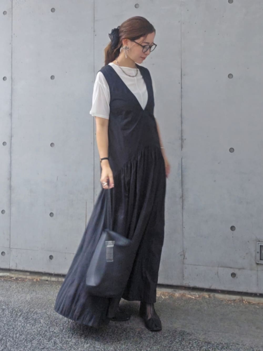 ブラック系のワンピース、ブラック系のブーツ、ブラウン系のメガネを着用したレディースの秋コーディネートの2枚目の写真