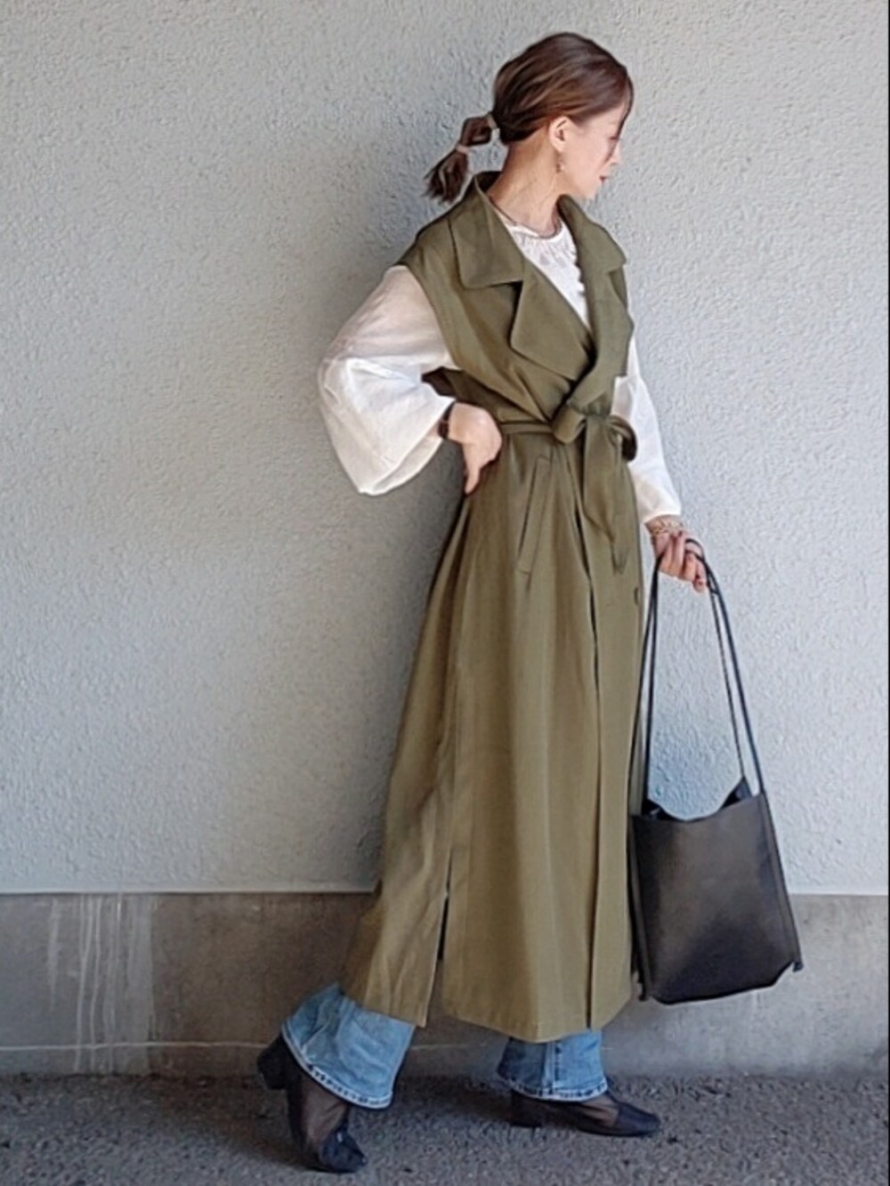 ブラック系のトートバッグ、ブラック系のブーツ、グリーン系のトレンチコートを着用したレディースの秋コーディネートの2枚目の写真