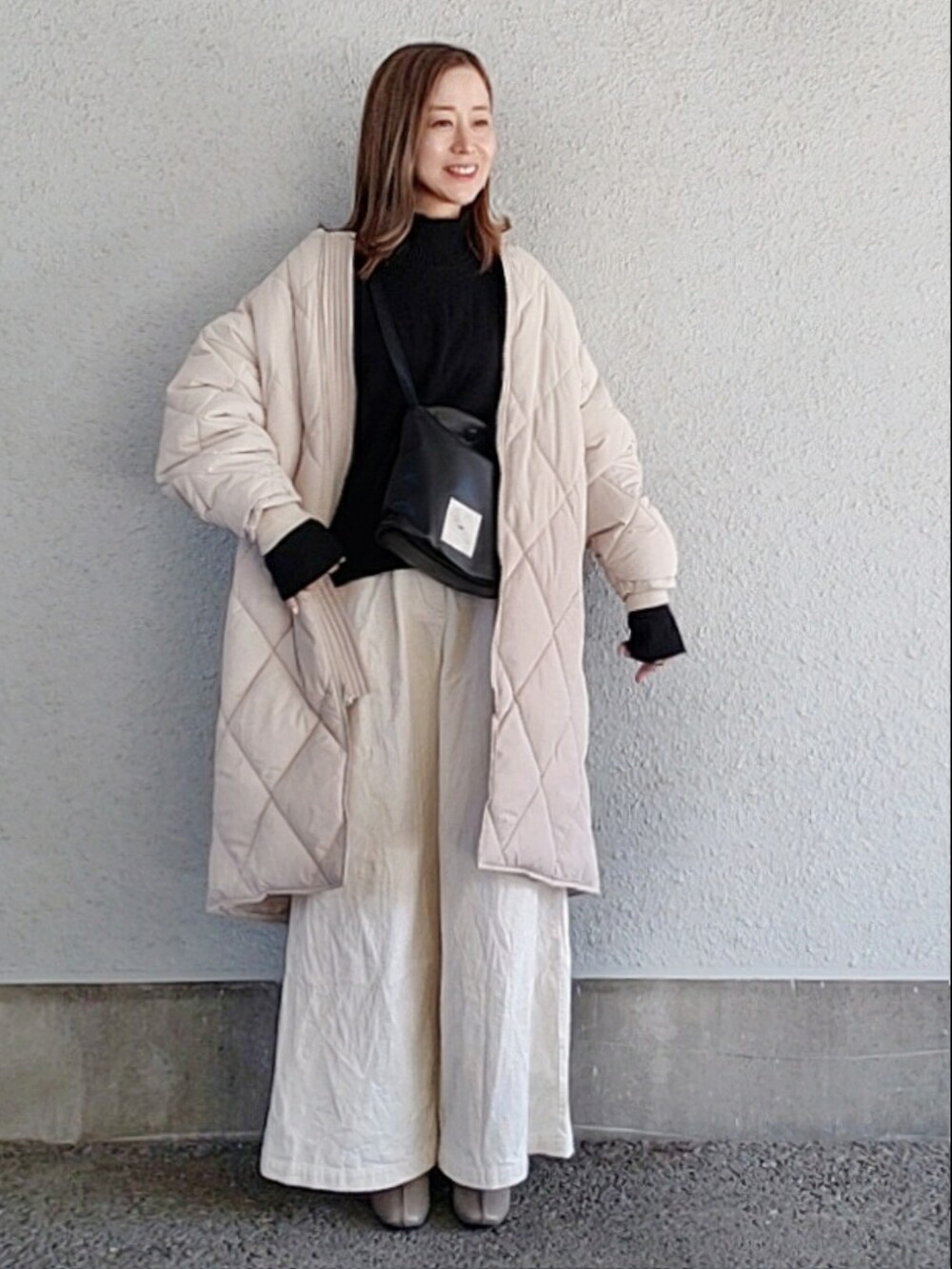 ホワイト系のダウンジャケット/コート、ブラック系のショルダーバッグ、ホワイト系のその他パンツを着用したレディースの冬コーディネートの2枚目の写真