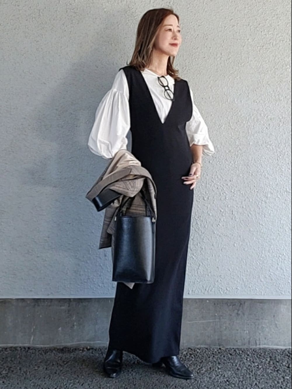 ブラック系のバッグ、ブラック系のワンピース、ブラック系のブーツを着用したレディースの冬コーディネートの3枚目の写真