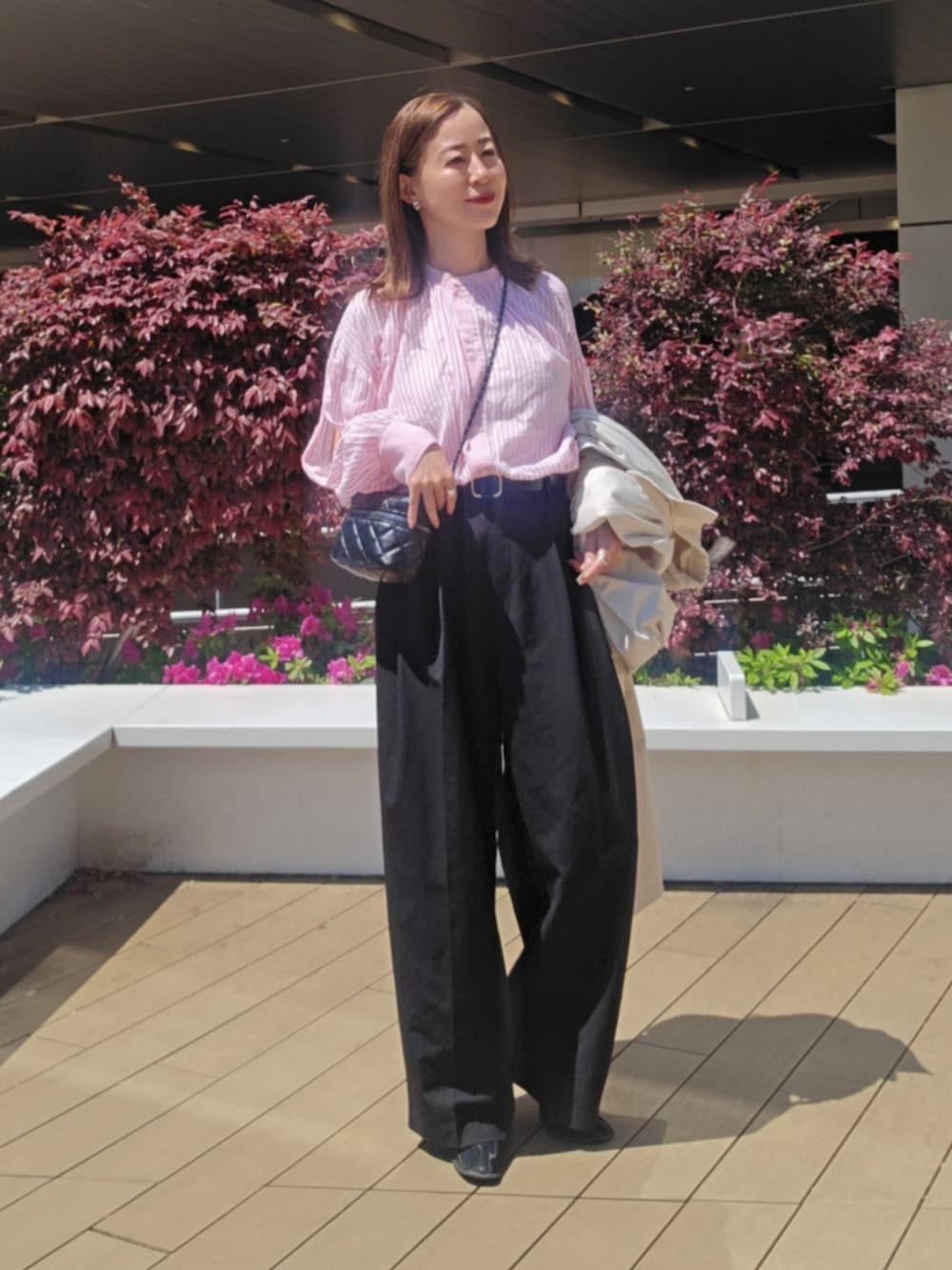 ピンク系のシャツ/ブラウス、ブラック系のスラックス、ブラック系のブーツを着用したレディースの春コーディネートの3枚目の写真