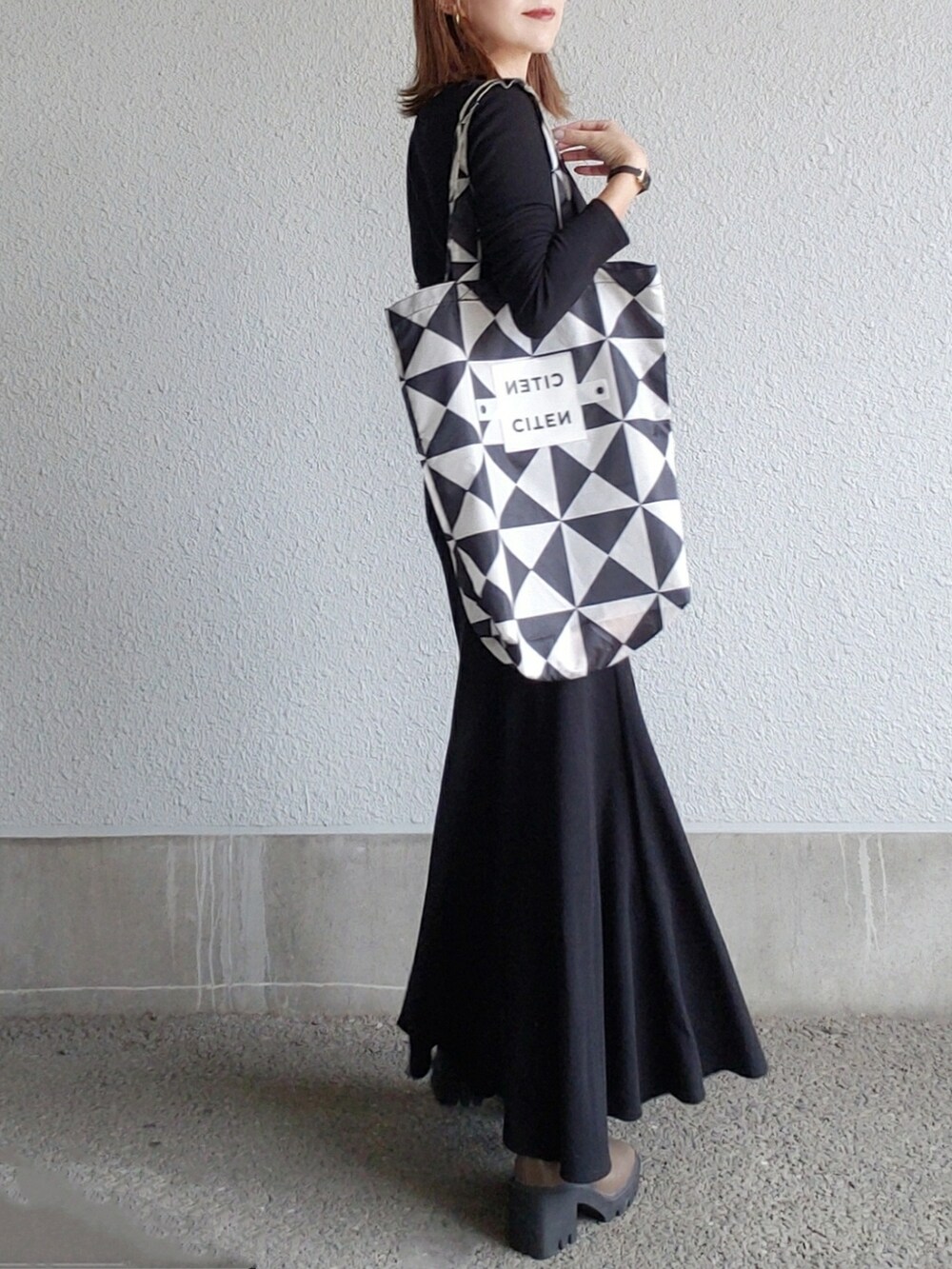 ブラック系のワンピース、ベージュ系のブーツ、ブラック系のトートバッグを着用したレディースの秋コーディネートの3枚目の写真