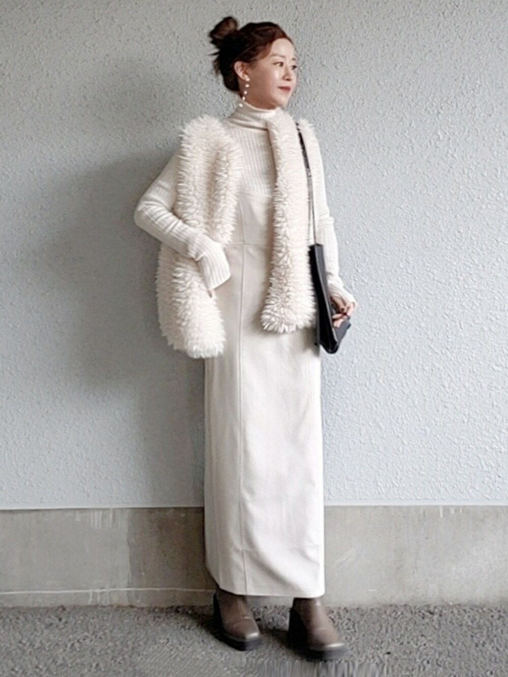 ホワイト系のワンピース、ホワイト系のベスト、ブラック系のトートバッグを着用したレディースの冬コーディネートの2枚目の写真