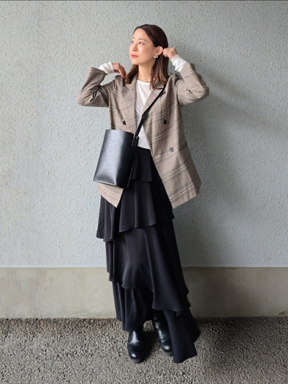 ブラック系のスカート、ブルー系のテーラードジャケット、ブラック系のバッグを着用したレディースの秋コーディネートの2枚目の写真