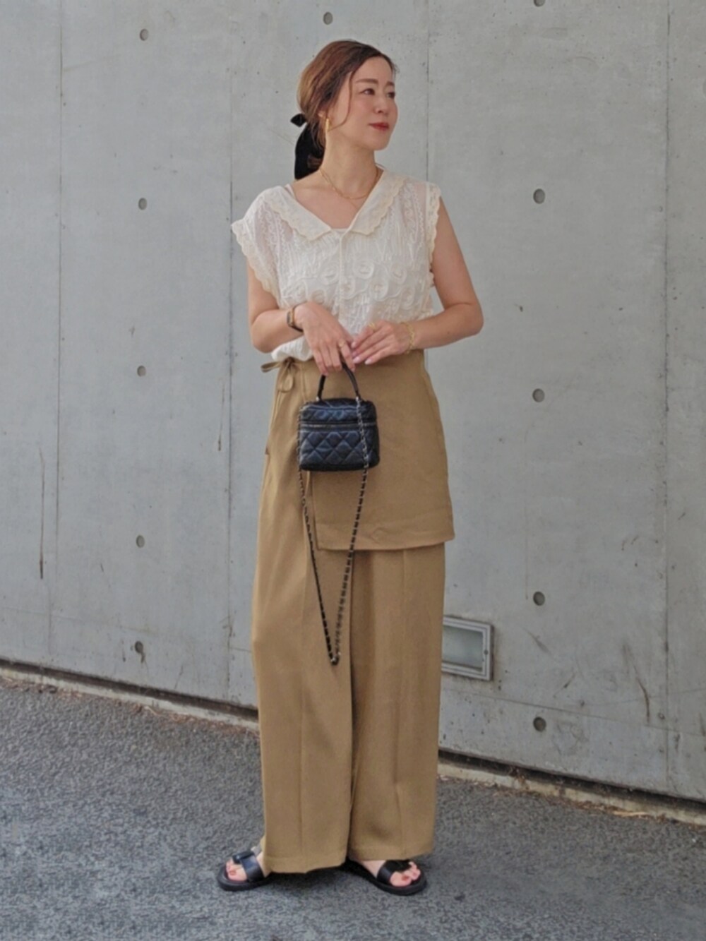 ホワイト系のシャツ/ブラウス、ベージュ系のスラックス、ブラック系のサンダルを着用したレディースの夏コーディネートの2枚目の写真