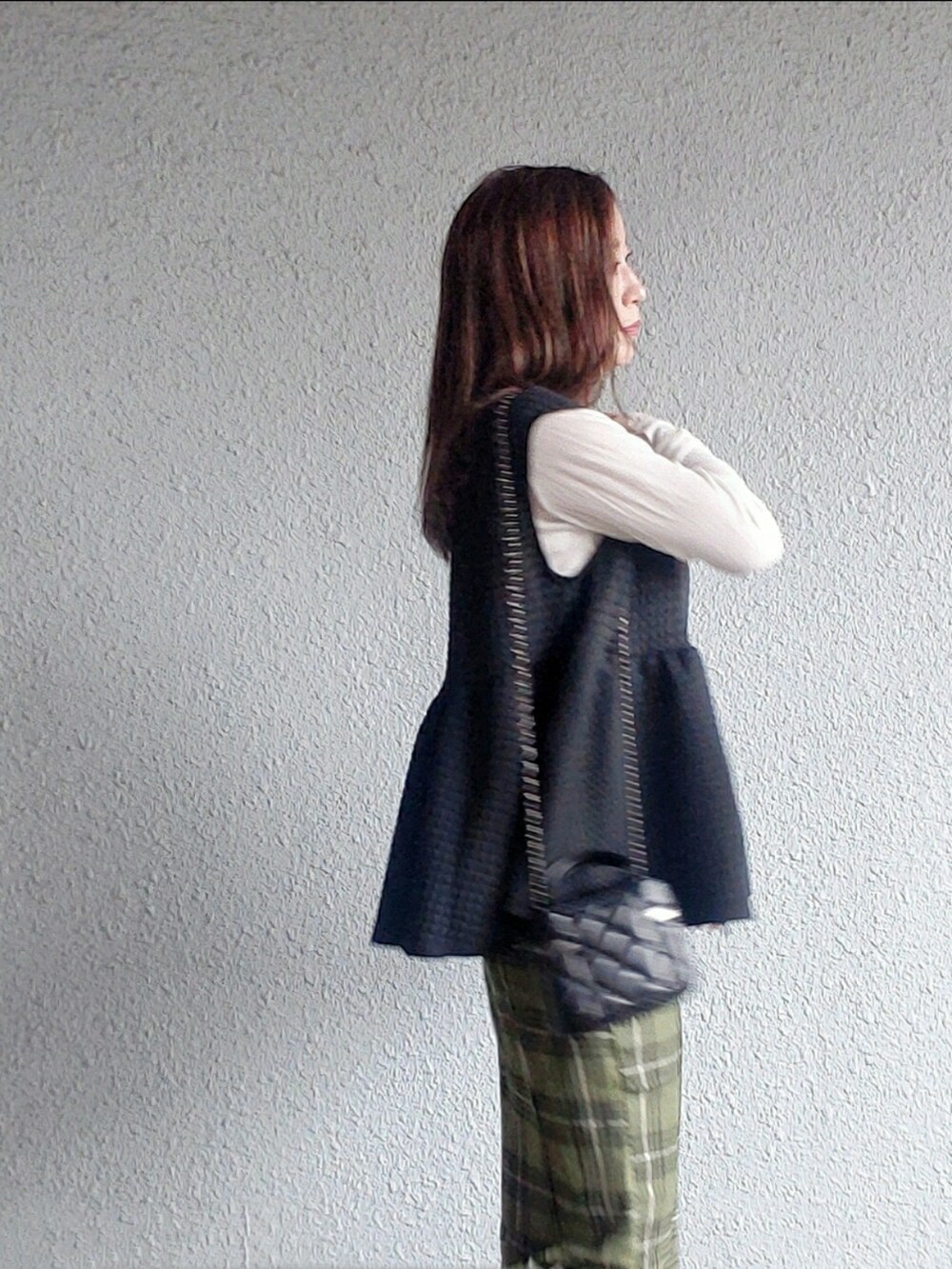 ブラック系のベスト、グリーン系のスカート、ブラック系のブーツを着用したレディースの秋コーディネートの4枚目の写真