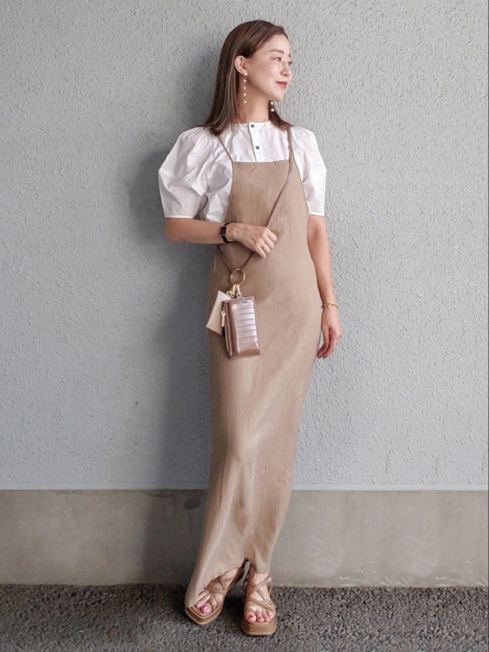 ベージュ系のワンピース、ブラウン系のサンダル、ホワイト系のシャツ/ブラウスを着用したレディースの夏コーディネートの2枚目の写真