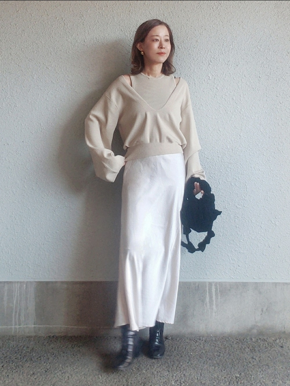 ベージュ系のニット/セーター、ブラック系のバッグ、ホワイト系のスカートを着用したレディースの春コーディネートの2枚目の写真