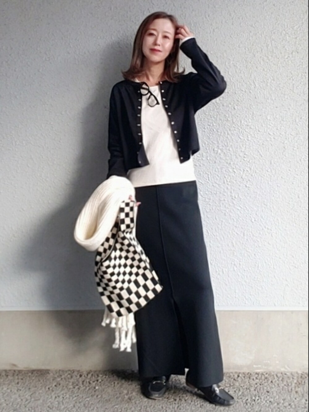 ブラック系のカーディガン/ボレロ、ブラック系のスカート、ブラック系のローファーを着用したレディースの冬コーディネートの3枚目の写真