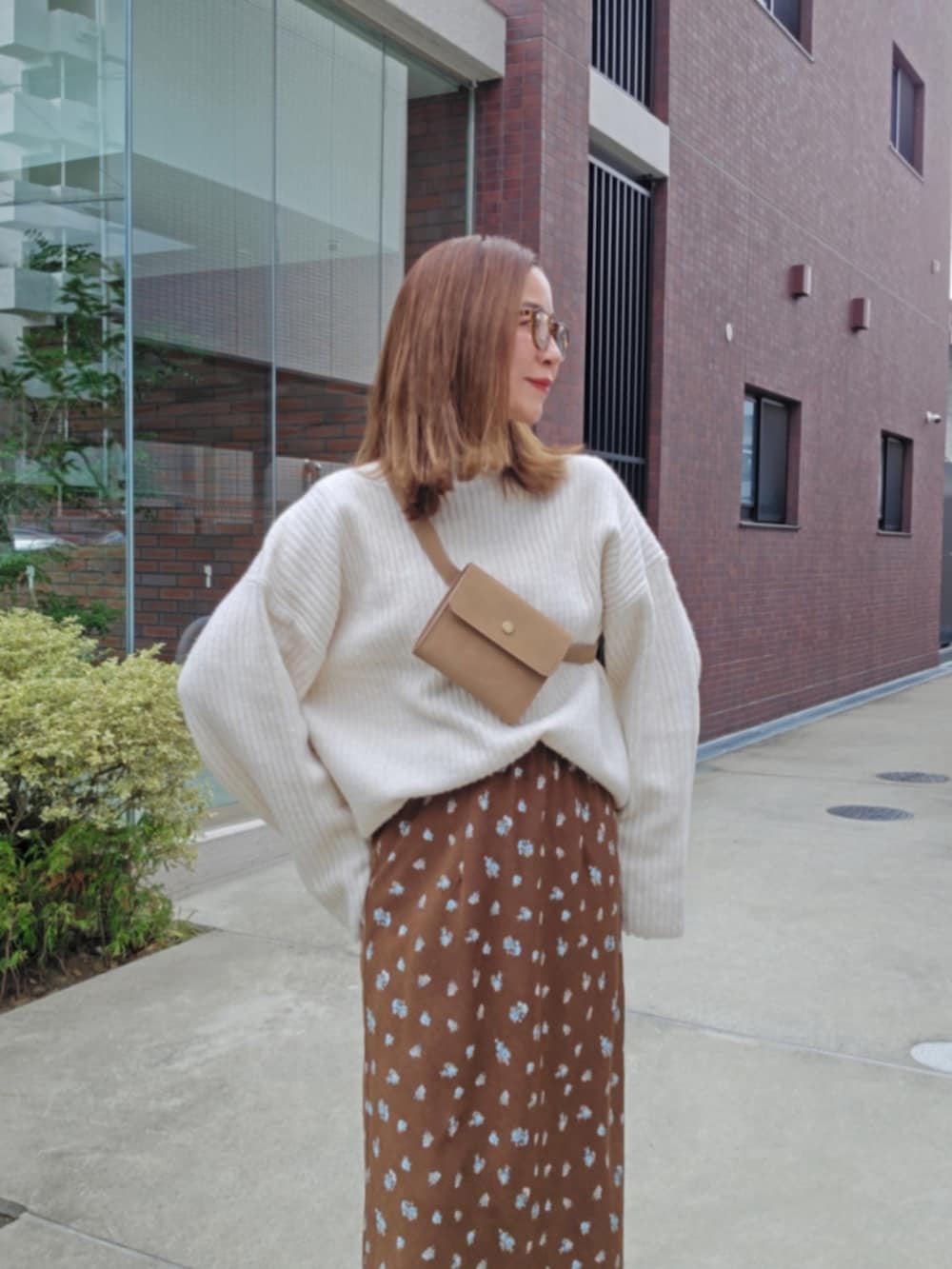 ブラウン系のスカート、ホワイト系のニット/セーター、ブラック系のブーツを着用したレディースの冬コーディネートの2枚目の写真