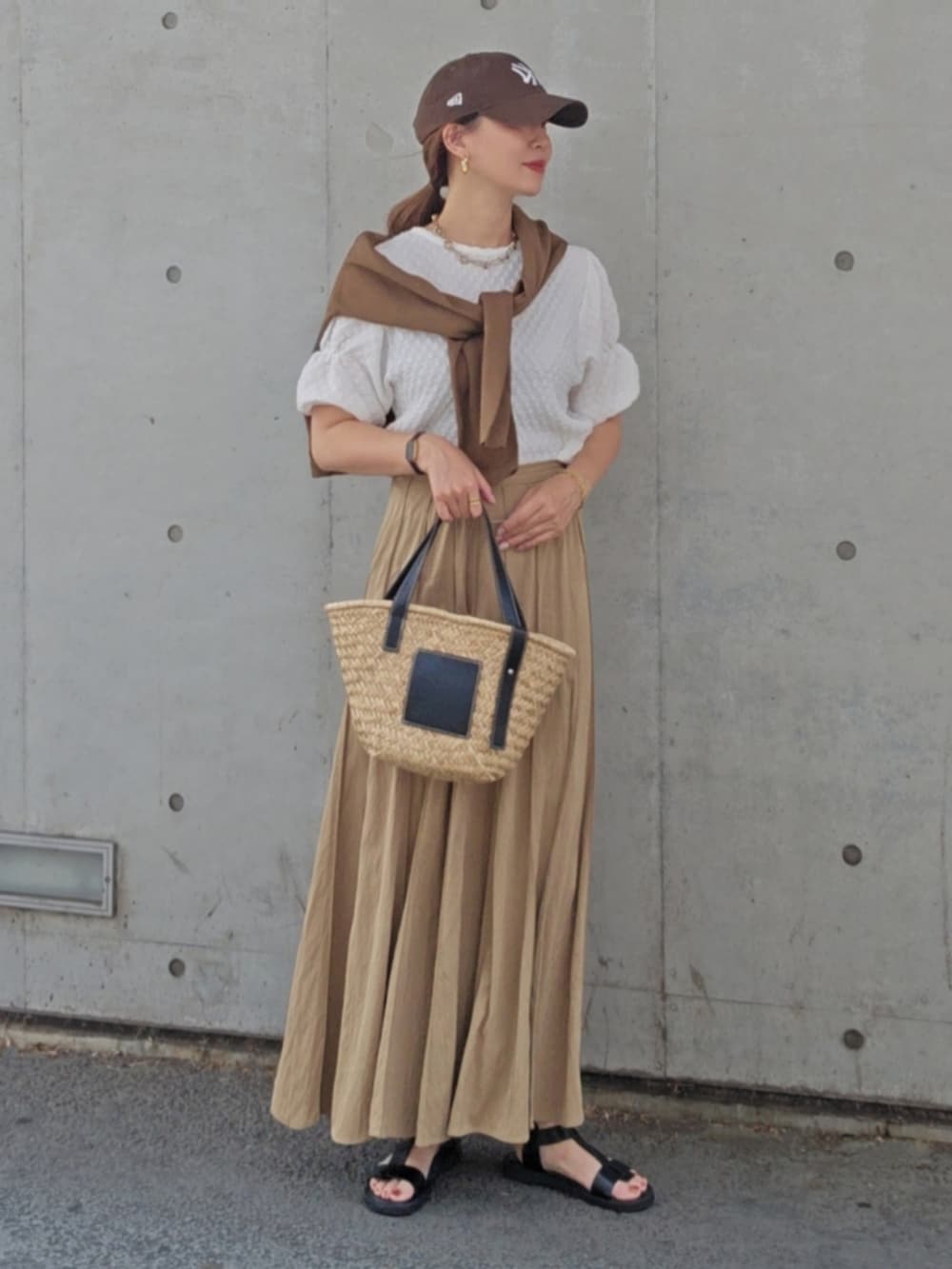 ベージュ系のスカート、ホワイト系のTシャツ/カットソー、ブラック系のかごバッグを着用したレディースの夏コーディネートの2枚目の写真