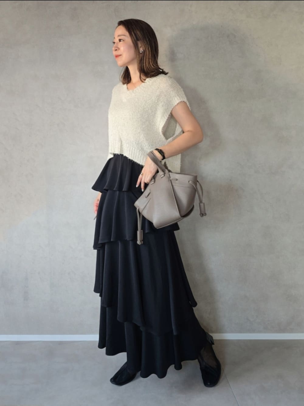 ブラック系のスカート、ブラック系のブーツ、ブラウン系のショルダーバッグを着用したレディースの秋コーディネートの2枚目の写真