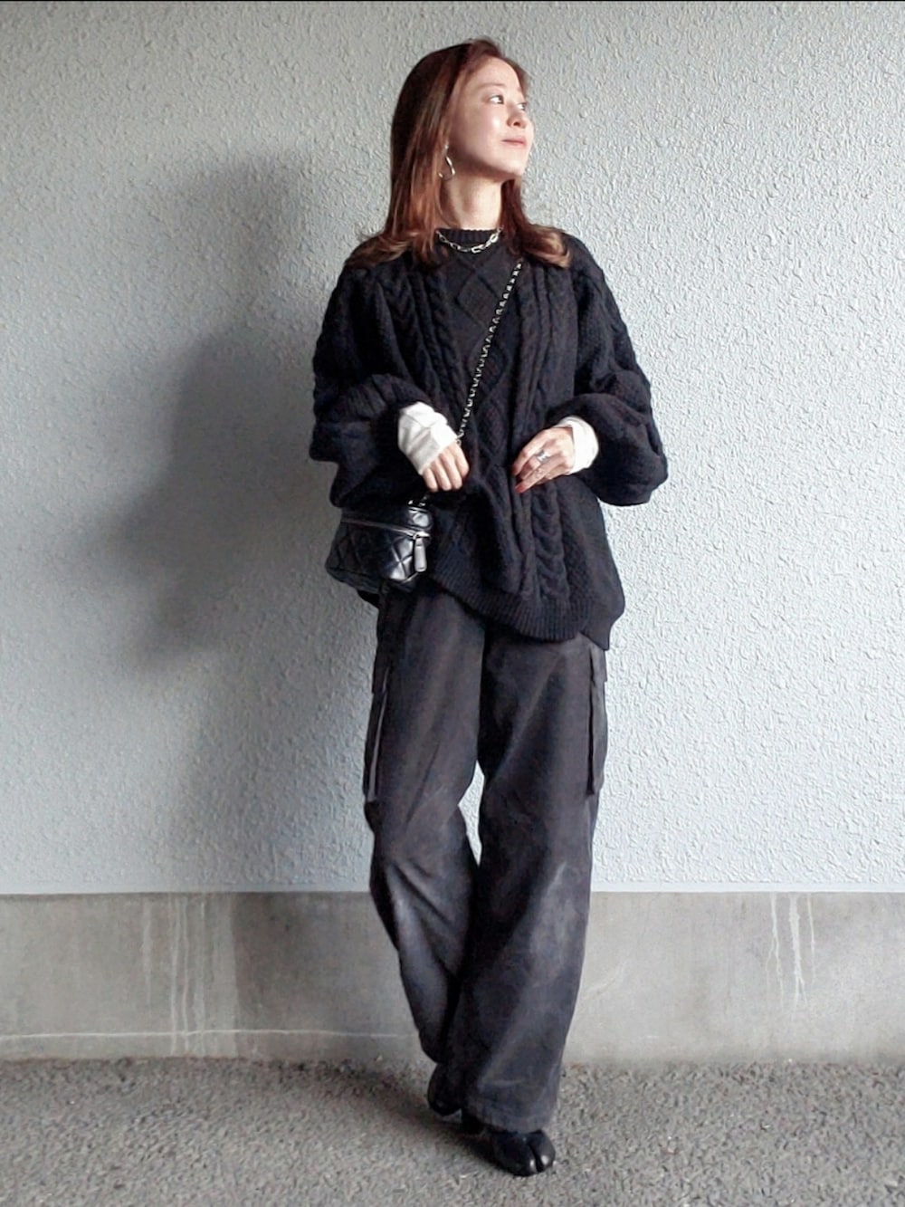 グレー系のパンツ、ブラック系のブーツ、ブラック系のニット/セーターを着用したレディースの秋コーディネートの2枚目の写真