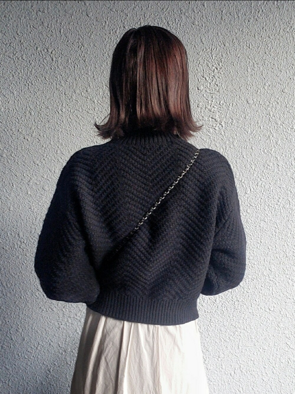 ブラック系のニット/セーター、ブラック系のバッグ、ベージュ系のトレンチコートを着用したレディースの秋コーディネートの5枚目の写真