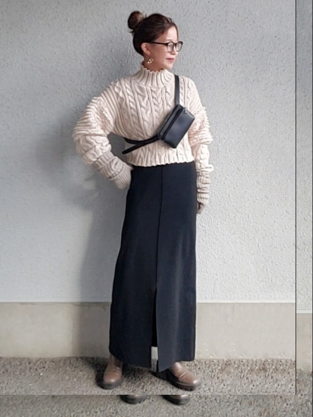 ブラック系のスカート、ベージュ系のブーツ、ホワイト系のニット/セーターを着用したレディースの冬コーディネートの3枚目の写真