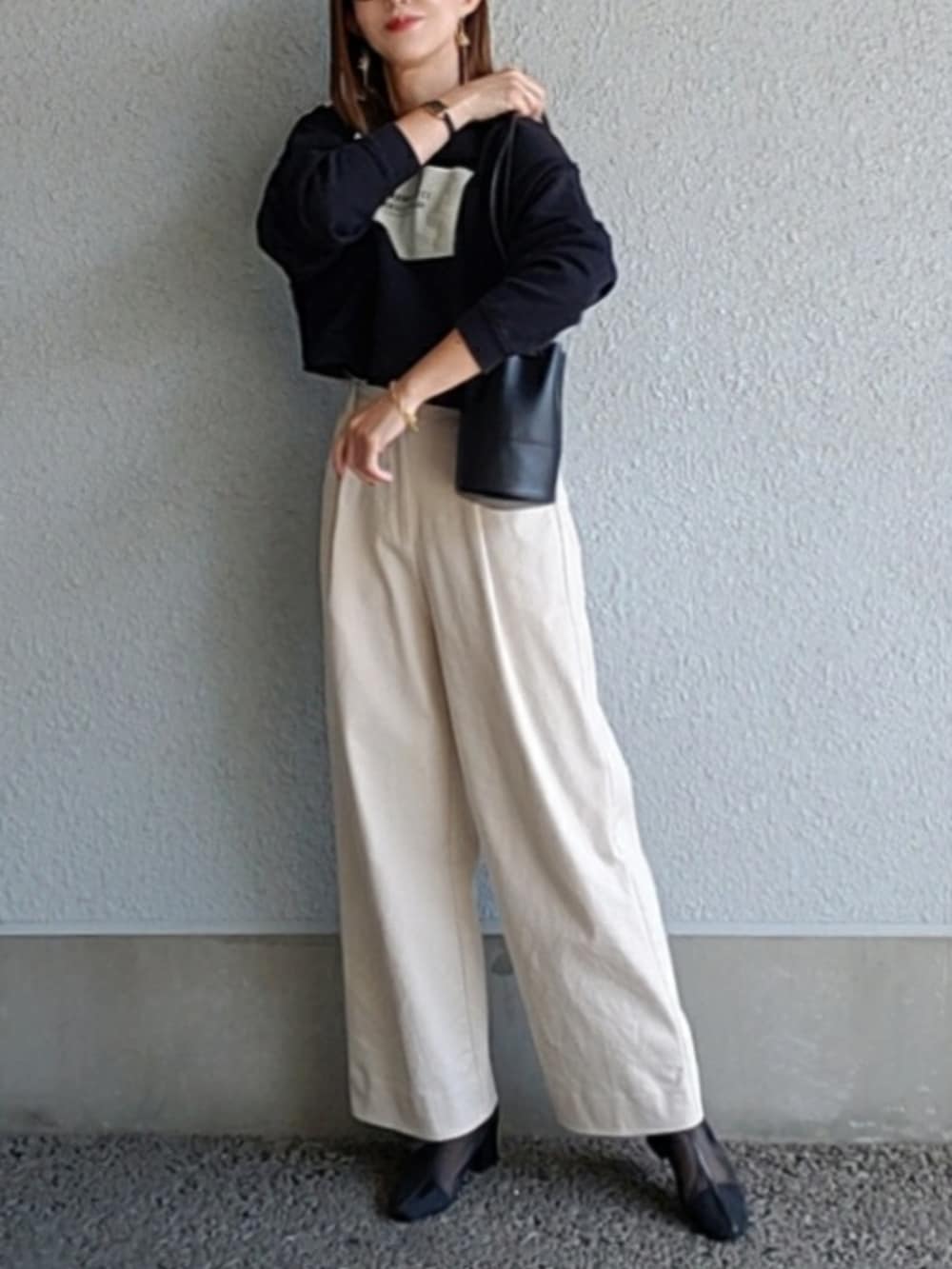 ブラック系のスウェット、ブラック系のハンドバッグ、ベージュ系のその他パンツを着用したレディースの秋コーディネートの2枚目の写真