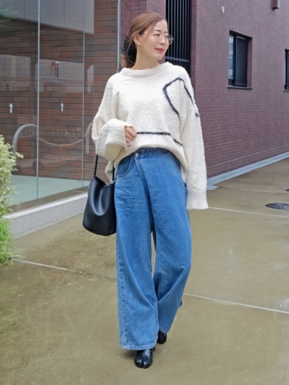 ホワイト系のニット/セーター、ブルー系のデニムパンツ、ブラック系のブーツを着用したレディースの秋コーディネートの2枚目の写真