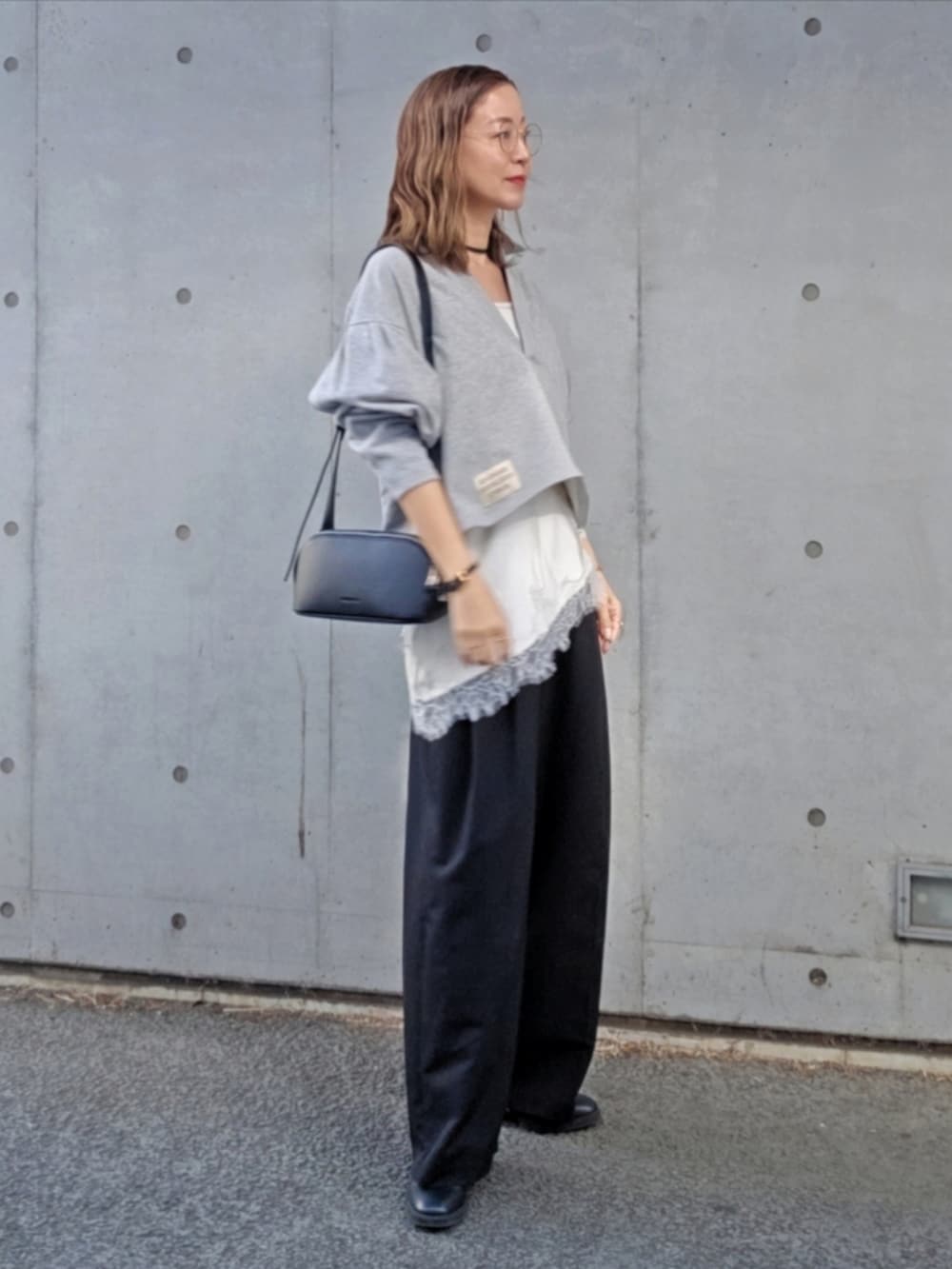 グレー系のスウェット、ブラック系のスラックス、ブラック系のショルダーバッグを着用したレディースの春コーディネートの2枚目の写真